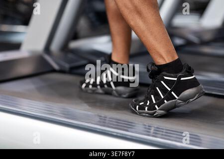 Cropped image of Black male working out using treadmill standing in gym during workout Stock Photo