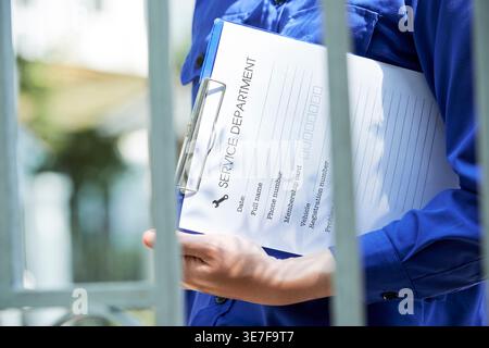 Cropped image of Asian repairman holding document while walking to house of client outdoors Stock Photo
