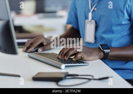 Cropped image of Black programmer typing on keyboard sitting at desk in office Stock Photo