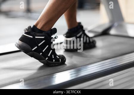 Cropped image of Black male working out using treadmill standing in gym during workout Stock Photo