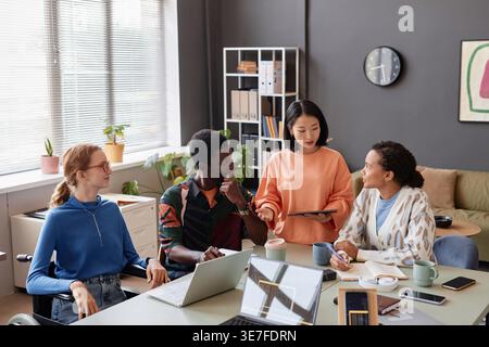 Diverse group of business people discussing work over tablet in office Stock Photo