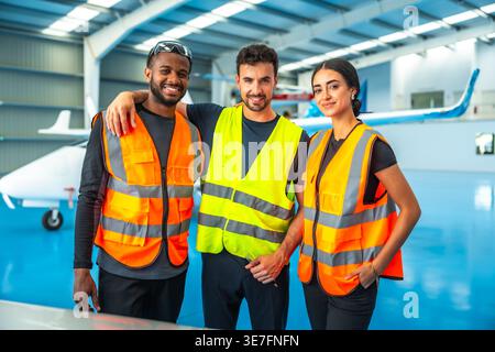 Diverse aircraft maintenance crews wearing reflective vest standing in hangar Stock Photo