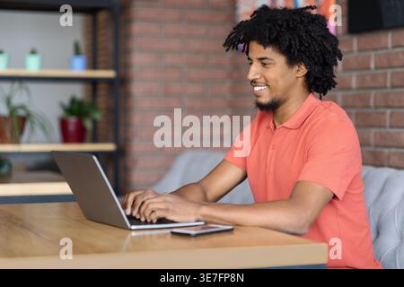 Black male with afro using laptop sitting at table in cafe Stock Photo