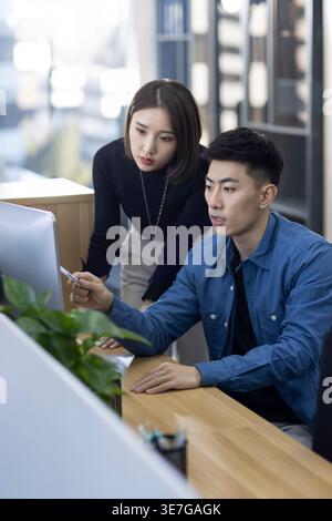 Chinese male and female IT experts working together on computer in office Stock Photo