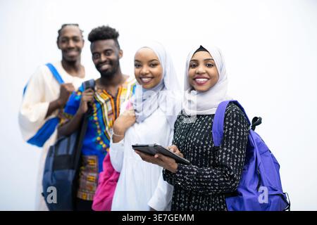 Smiling Black and Muslim college students standing with backpacks against white background in studio Stock Photo