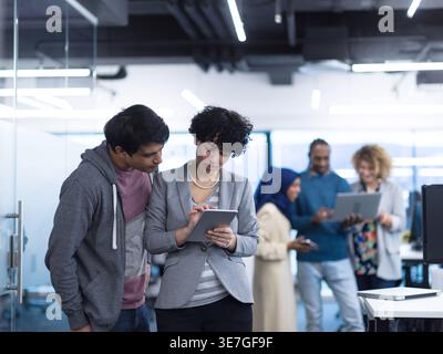 Mixed race male and female workmates working together on tablet standing in office Stock Photo