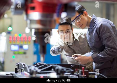 Chinese male engineers checking machine in factory Stock Photo