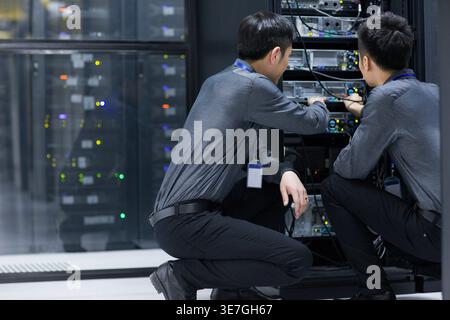 Chinese male technicians doing maintenance in computer room Stock Photo