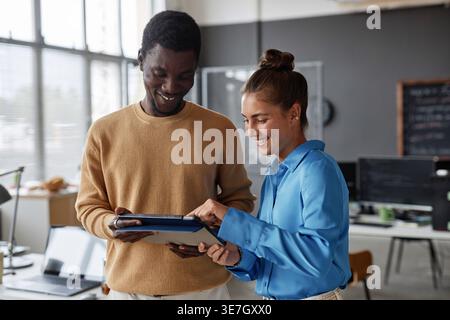 Black male and caucasian female programmers using tablet while standing in office Stock Photo