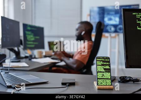 Black male programmer looking at computer with codes while sitting at table in office Stock Photo