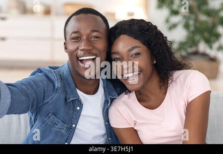 Closeup portrait of african lovers taking selfie together, resting at home Stock Photo