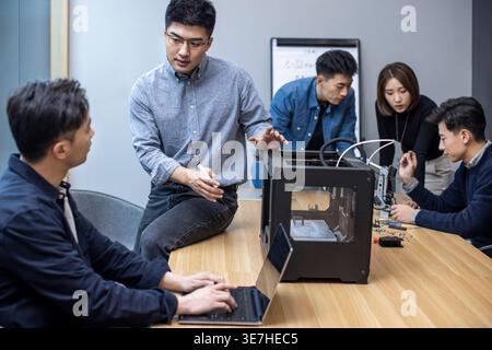 Chinese IT experts using 3D printer in making robotic arm in office Stock Photo