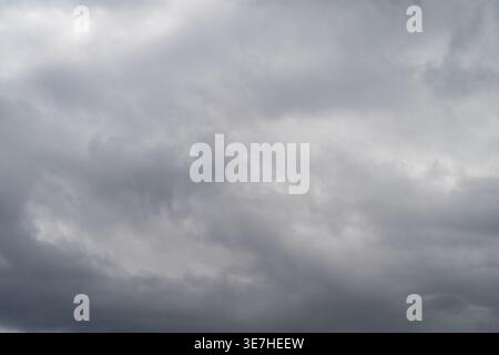 Gloomy sky cover. Dark clouds blanket muted scenery. Cloudy gray sky over subdued landscape. Overcast skies with dense cloud cover obscuring dull envi Stock Photo