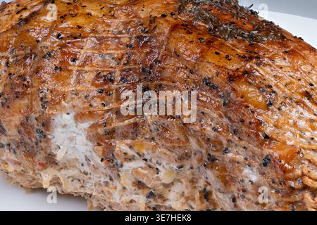 Closeup seasoned roasted pork with spices, crisp caramelized crust coated in pepper and herbs, visible netting marks, tender juicy interior hinted, hi Stock Photo