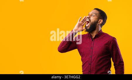 Black man looking away and shouting while standing against yellow background in studio Stock Photo