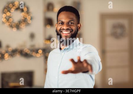 Black man with beard reaching out hand while standing at home Stock Photo