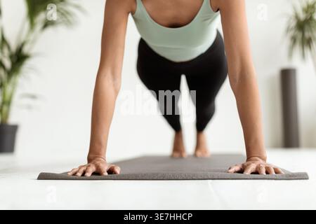 Cropped image of Middle Eastern woman doing push ups on fitness mat at home Stock Photo