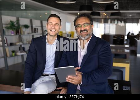 Happy staff members with digital tablet posing for camera Stock Photo