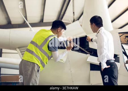 Chinese airplane mechanic checking helicopter with his apprentice in airport Stock Photo