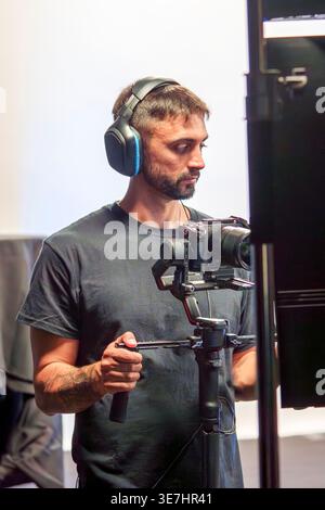 Hispanic cameraman wearing headphones recording video using camera in studio Stock Photo