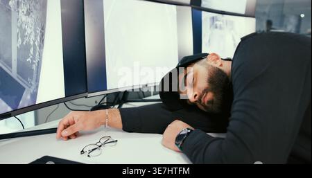 Man, security guard and sleep in control room with screen for job, tired and exhausted with overtime. Person, surveillance and safety officer with Stock Photo
