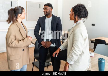Black businessman holding laptop having meeting with female colleagues in office Stock Photo