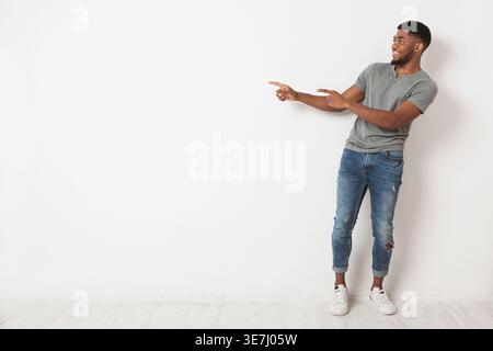 Its great. Smiling african-american man pointing two fingers aside at copy space, white studio background Stock Photo
