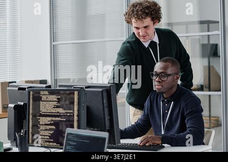 Black and caucasian male programmers discussing new program codes on computer during work in office Stock Photo