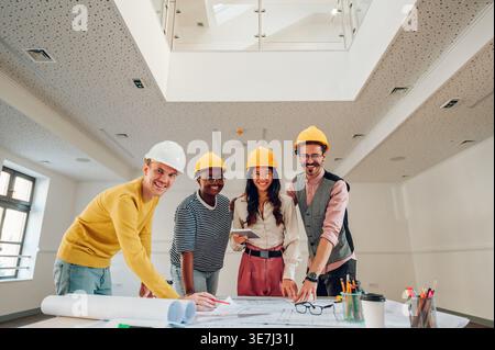 Close-up shot cheerful Diverse group of architects smiling and standing in the working area of the office Stock Photo