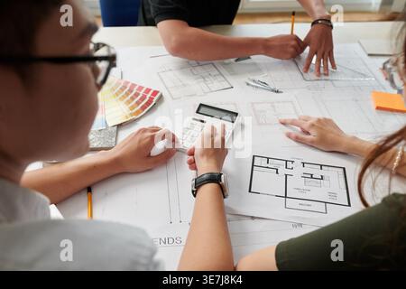 Team of Asian architects and interior designers working on house blueprint sitting at desk in office Stock Photo