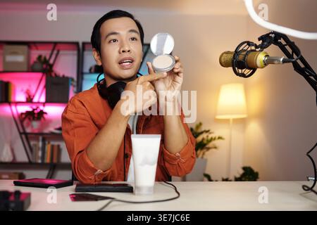 Asian man recording content for video blog making review of cosmetic products at home Stock Photo