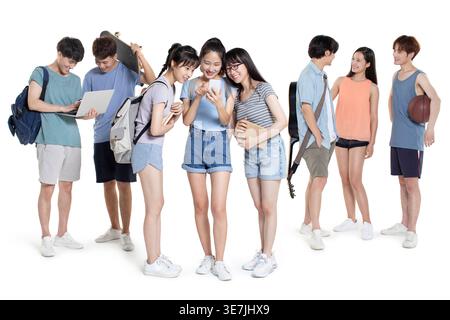 Group of Chinese male and female students using smartphone while talking standing against white background in studio Stock Photo