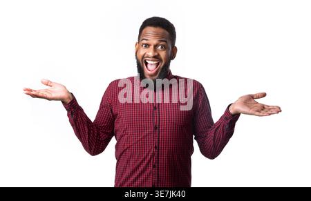 Black bearded man wearing red and blue checkered long sleeves spreading hands while standing with open mouth against white background in studio Stock Photo
