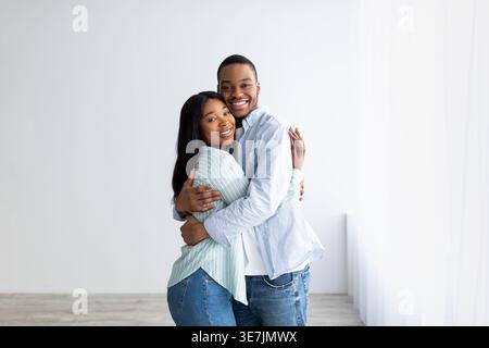 Smiling Black couple embracing each other while standing at home Stock Photo