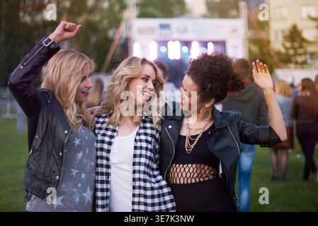 Diverse female friends dancing together in park during festival Stock Photo