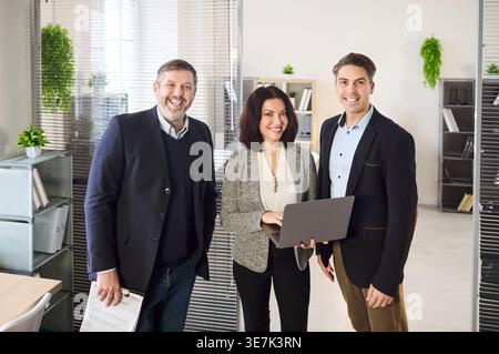 Smiling business colleagues collaborating with laptop during casual office meeting Stock Photo