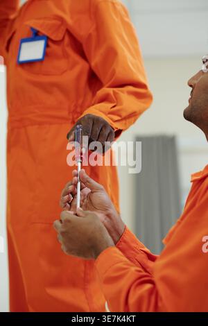 Indian male technician giving screwdriver to Black male coworker while standing in house of customer Stock Photo