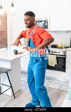 Happy young man dancing and enjoying music in his modern kitchen, expressing freedom and happiness through urban dance moves Stock Photo