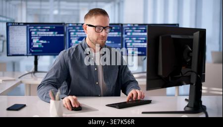 Focused Software Developer Programming At Office Desk Stock Photo