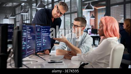 Software Engineer Writes Code Carefully While Collaborating With Colleagues Closely. Stock Photo