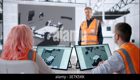 Engineer Explains New Electric Car Model Using Tablet During Team Meeting. Stock Photo