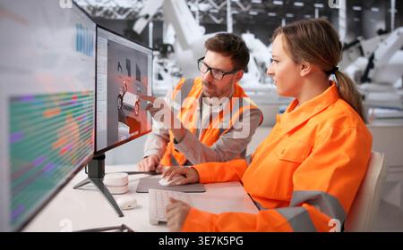 Automotive Engineer Working On Computer In Factory To Develop New Vehicle Model Stock Photo