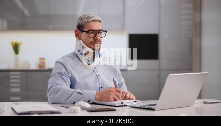 Injured Worker Submitting Accident Report Via Laptop In Workplace Environment Stock Photo