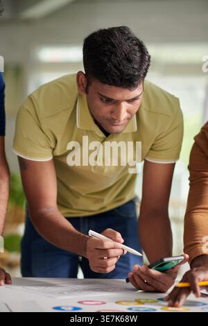 Group of Asian male designer leaning on table working together in office during daytime Stock Photo
