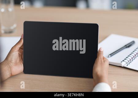 Hands of Black woman holding tablet on table at home office Stock Photo