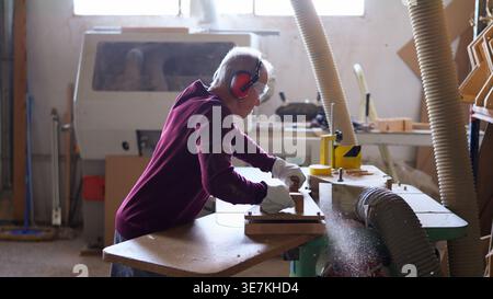 Woodworker shaping wood piece using wood shaper in workshop Stock Photo
