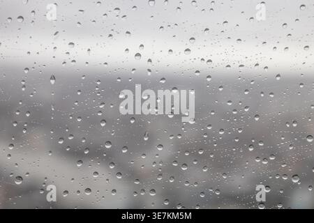 Close up of water droplets on glass during a gray rainy day Stock Photo