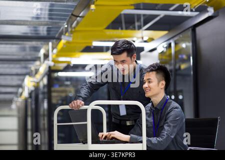 Chinese male technicians doing maintenance using laptop in computer room Stock Photo