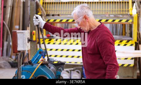 Senior craftsman operating woodworking machinery in workshop Stock Photo