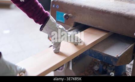 Worker planing wood plank using thickness planer in workshop Stock Photo